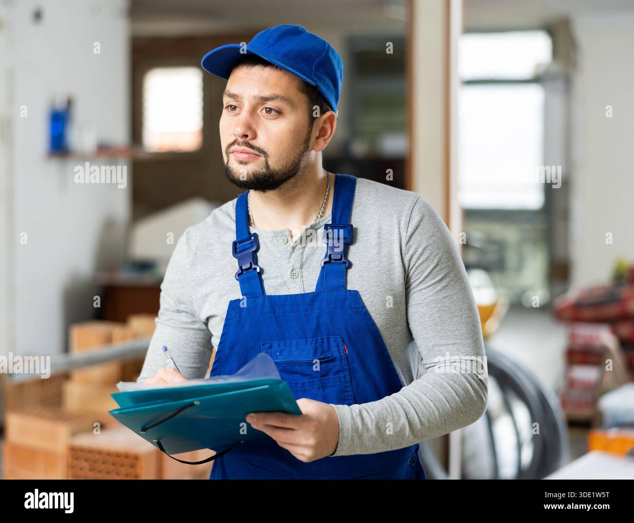 Builder making notes on indoor construction site Stock Photo