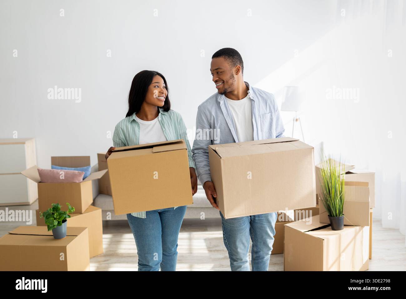 Relocation and apartment rent. Loving african american spouses carrying paper boxes into new house Stock Photo