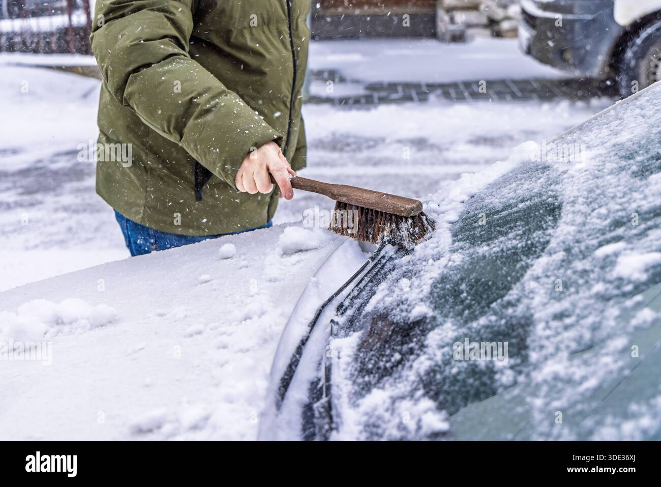 Removing snow from car windshield. Clean car window in winter from snow. Stock Photo