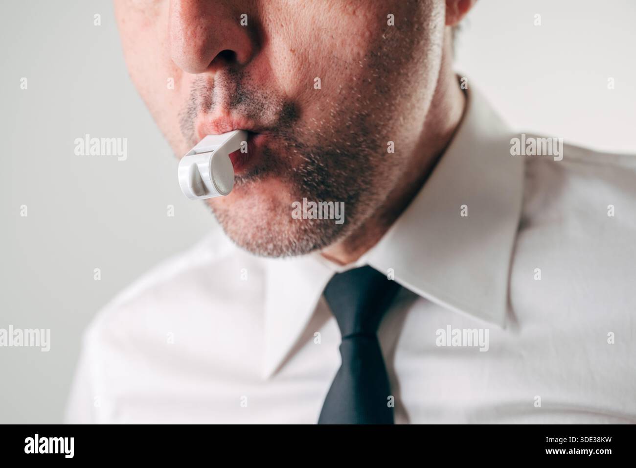 whistle cigarette Close-up of a businessman blowing a whistle, symbolizing whistleblowing,  ethics, accountability, and reporting misconduct in corporate or  professional Stock Photo
