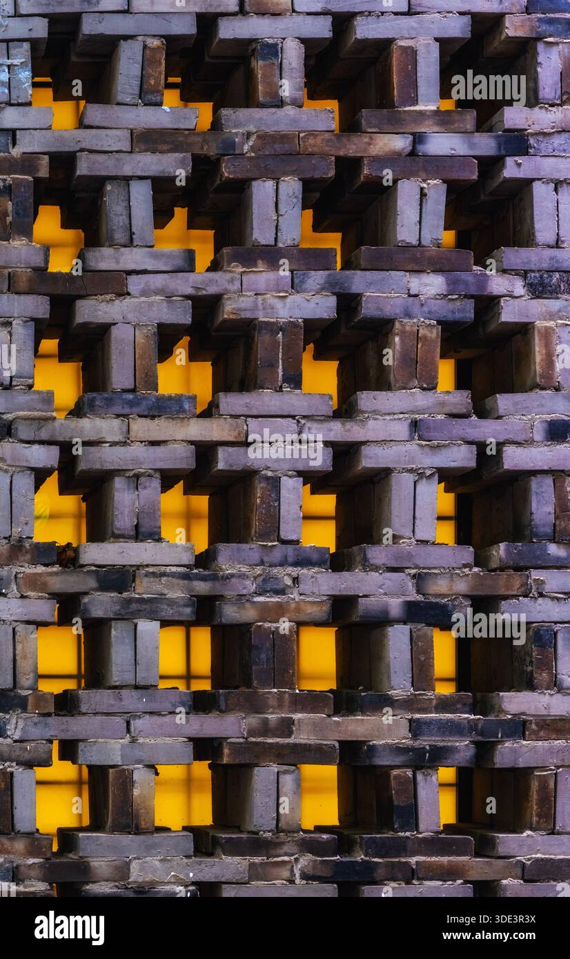 a textured brick wall featuring a complex, three-dimensional pattern. The bricks are arranged in a staggered, interlocking design, creating a series o Stock Photo