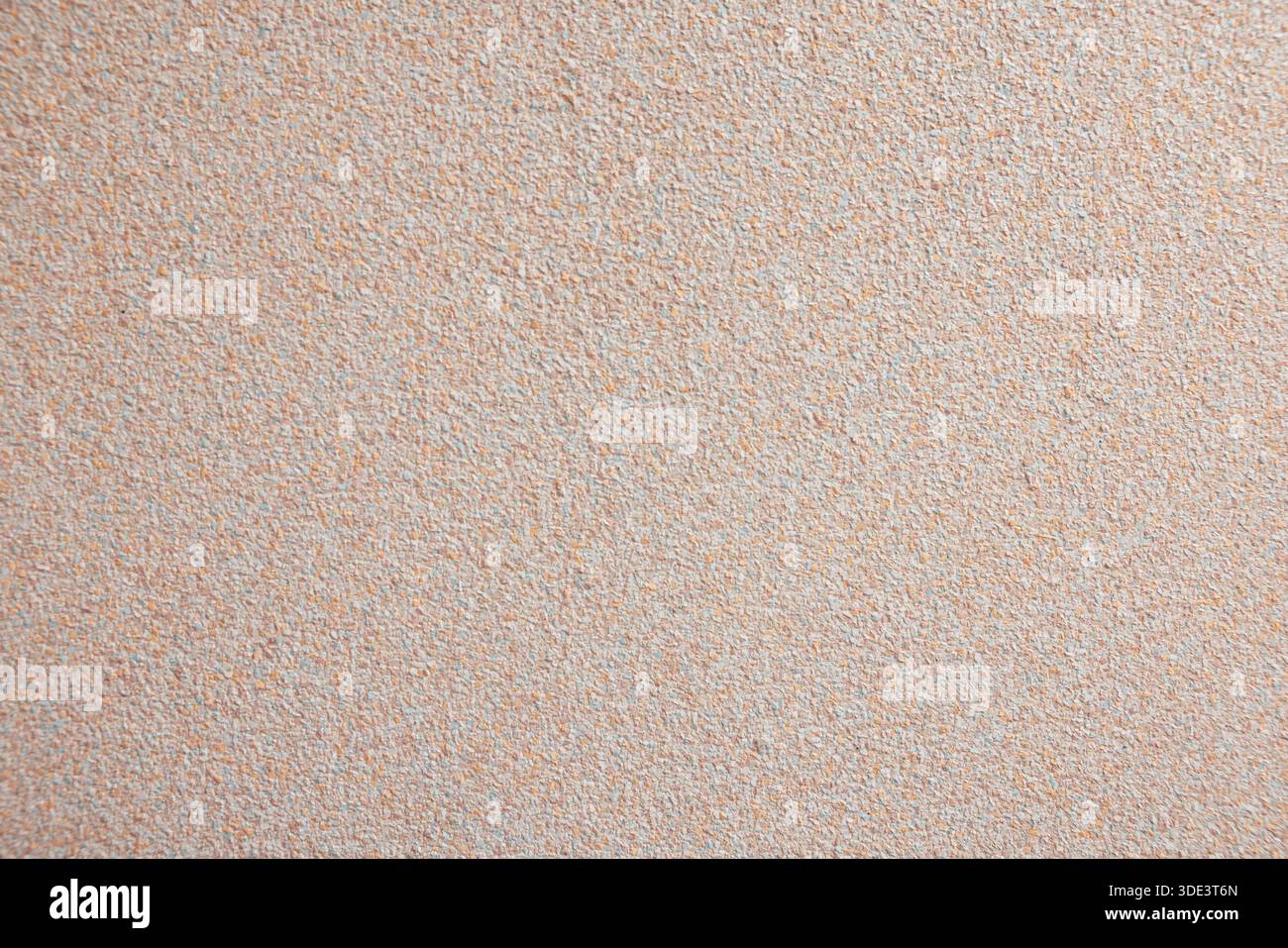 A textured beige wall background with a subtle grainy appearance. The surface is smooth and uniform, suitable for various design applications. Stock Photo