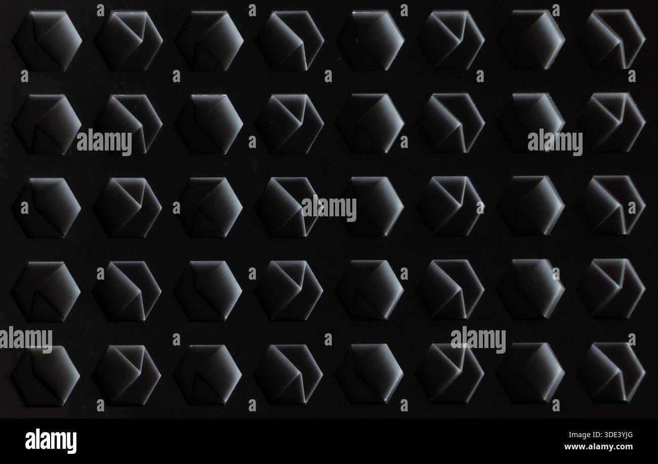 a white, textured surface featuring a grid of hexagonal indentations. Each hexagon has a three-dimensional, geometric design with internal triangular Stock Photo
