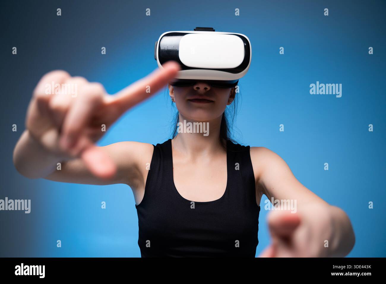 Young woman wearing VR headset with arms extended, immersive virtual  reality interaction in blue studio lighting Stock Photo - Alamy
