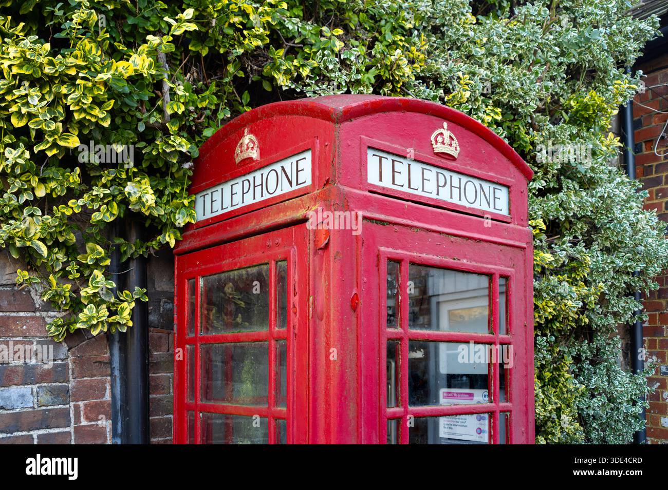 Avebury, United Kingdom - December 27, 2025: Classic red British telephone booth in Avebury surrounded by greenery. Stock Photo