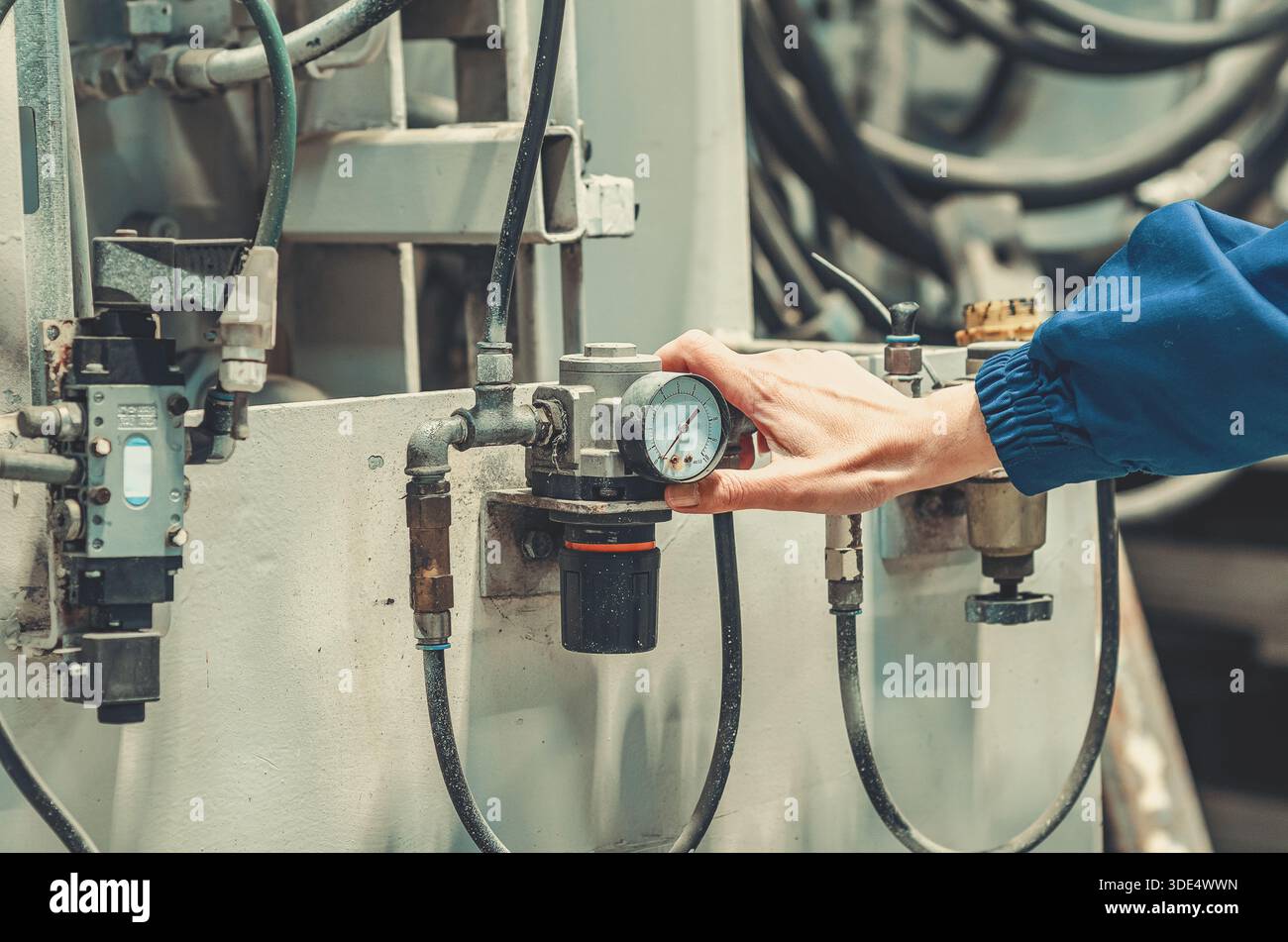 Technician hand adjusting pressure regulator with gauge on industrial ...