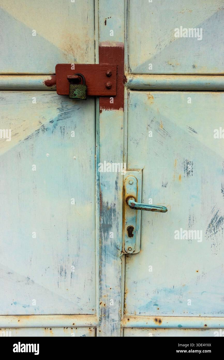 Old padlock securing a metal door, showing rust, wear, and industrial security Stock Photo