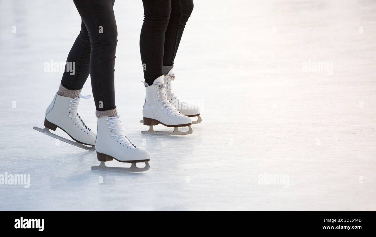 Closeup of womens legs on skates on open skating rink. Winter time, outdoor activities  Stock Photo