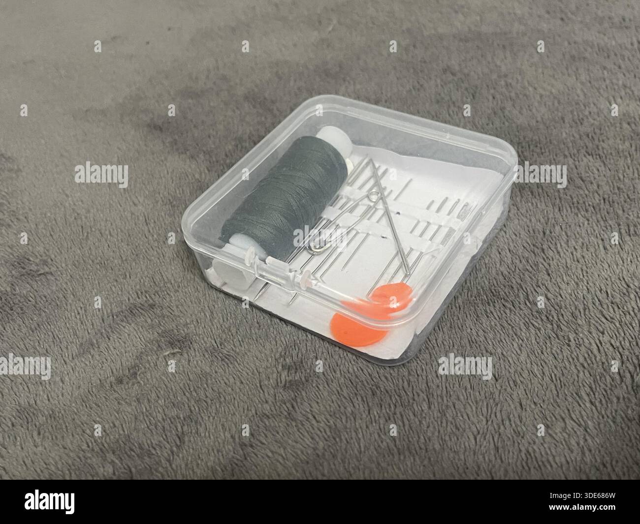 A tailor's sewing kit on a table. Needles, thread, and fabric for sewing. Stock Photo