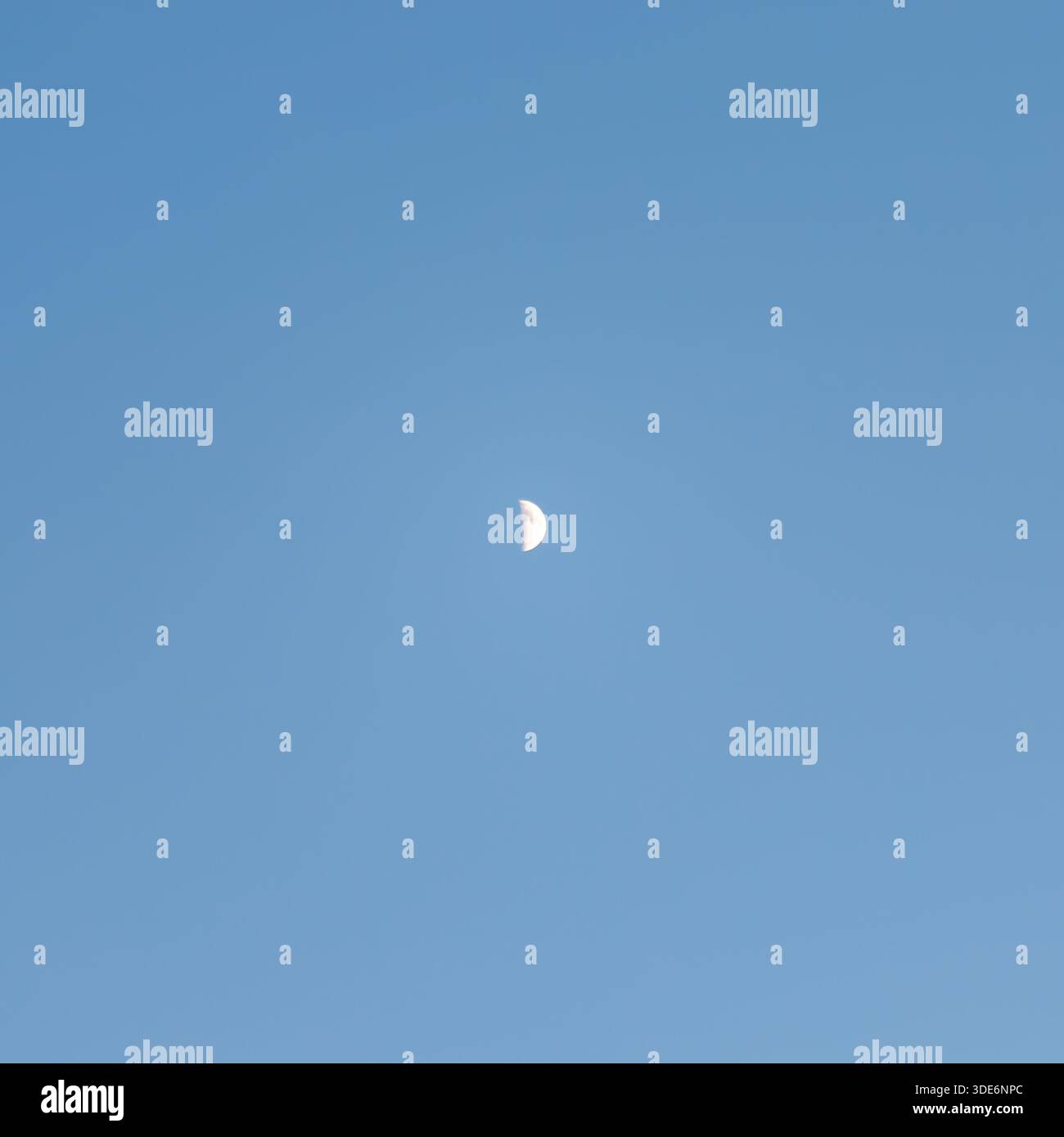 Half moon appearing in clear blue sky during daylight Stock Photo
