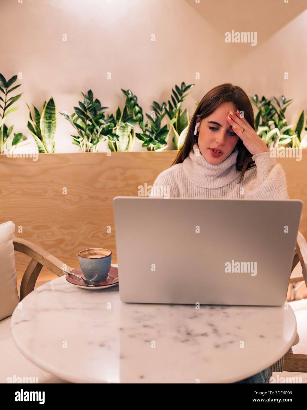 Woman suffering headache using laptop in remote workspace Stock Photo