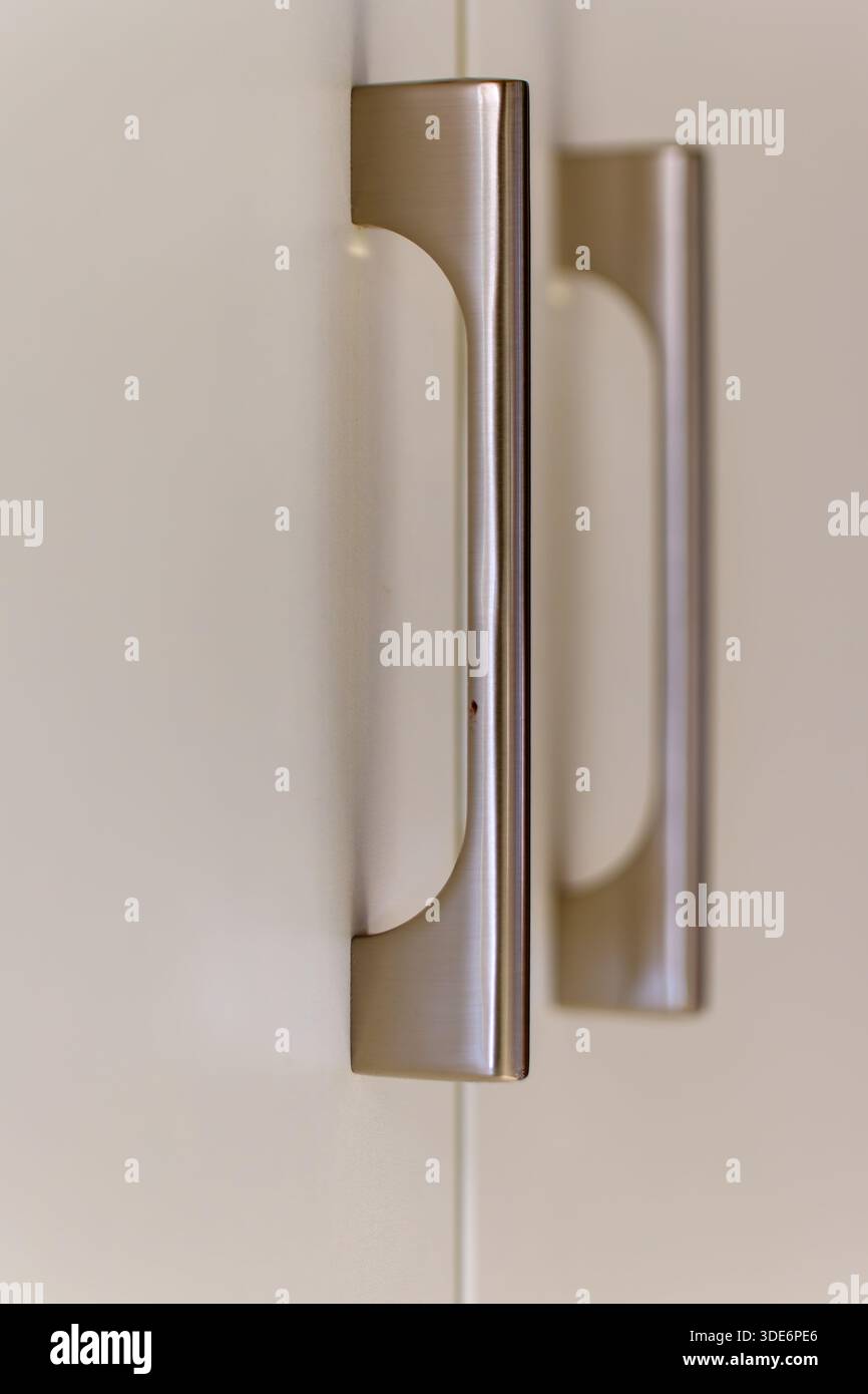 Brushed metal cabinet handles providing a contemporary detail to storage furniture Stock Photo