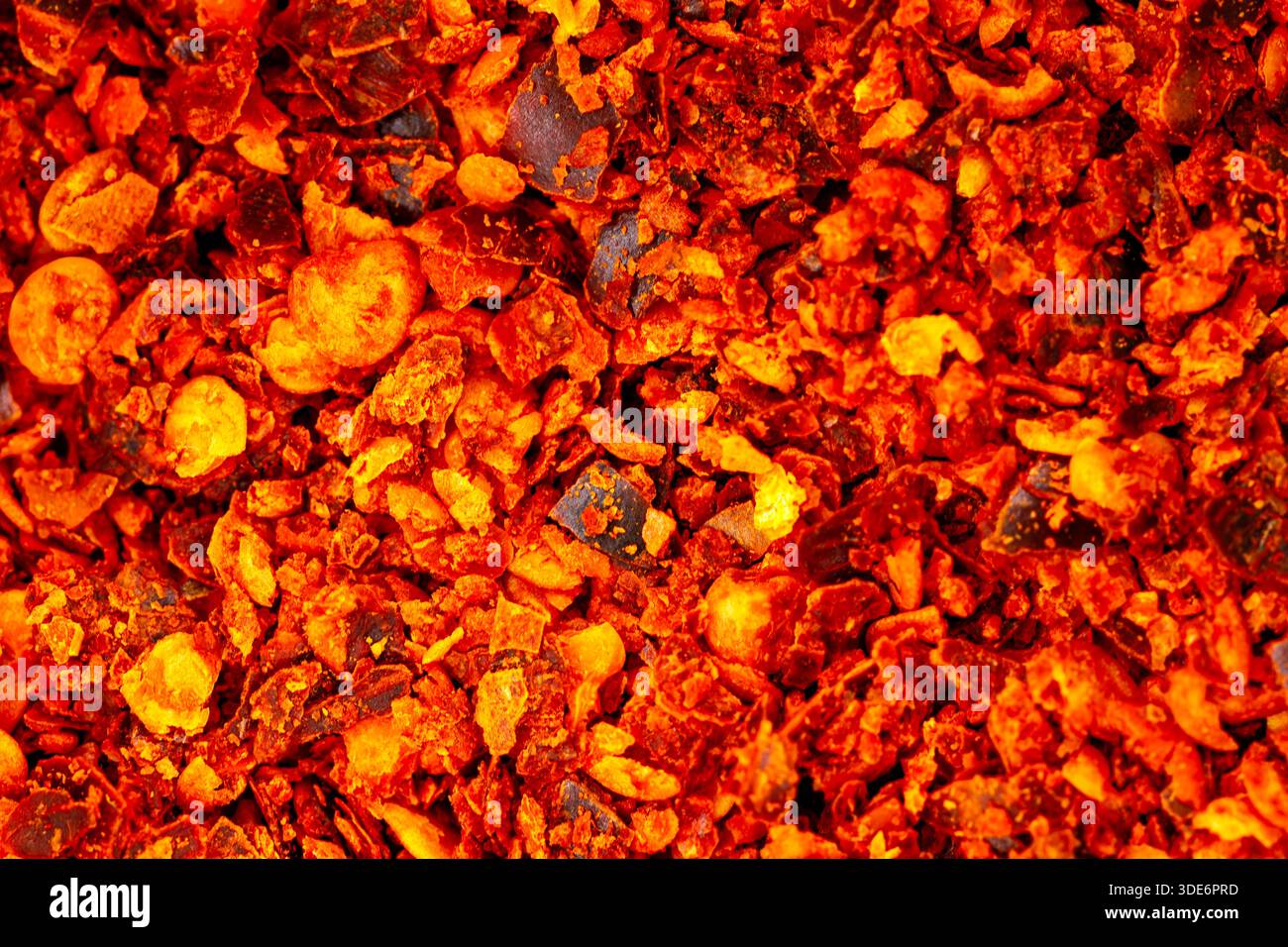 Red chili flakes creating a hot, textured background Stock Photo