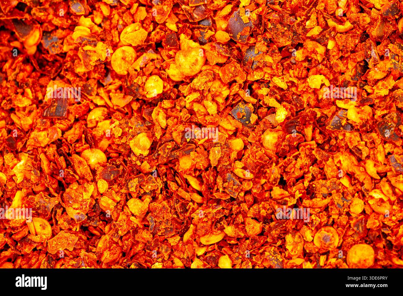 Crushed red pepper flakes creating a vibrant fiery texture background Stock Photo