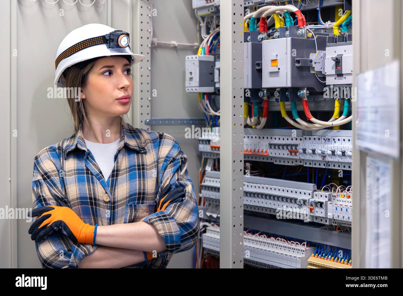 Female engineer inspecting electrical cabinet in control room. Panel inspection. Stock Photo
