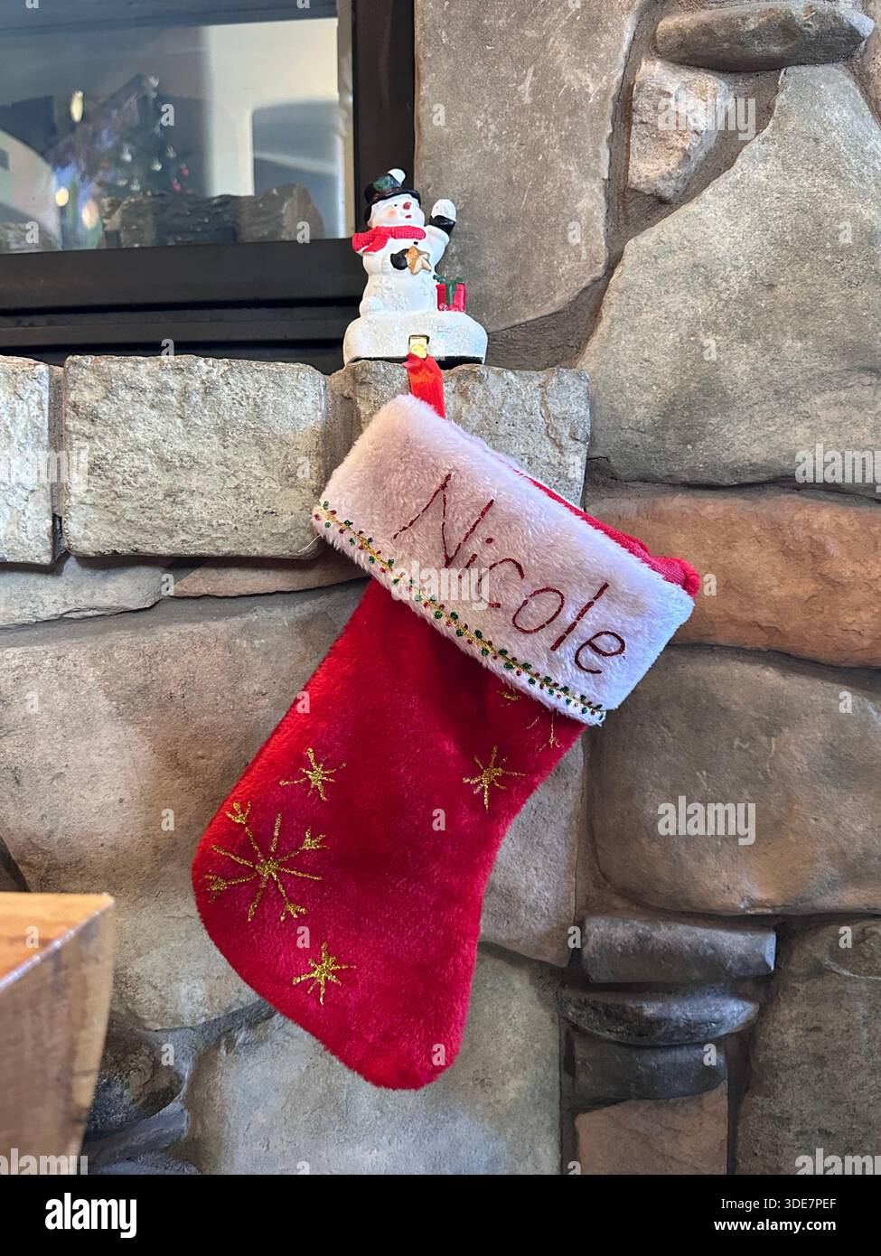 Personalized Christmas Stocking Hanging on Stone Fireplace written Nicole - Smartphone Captured Stock Image