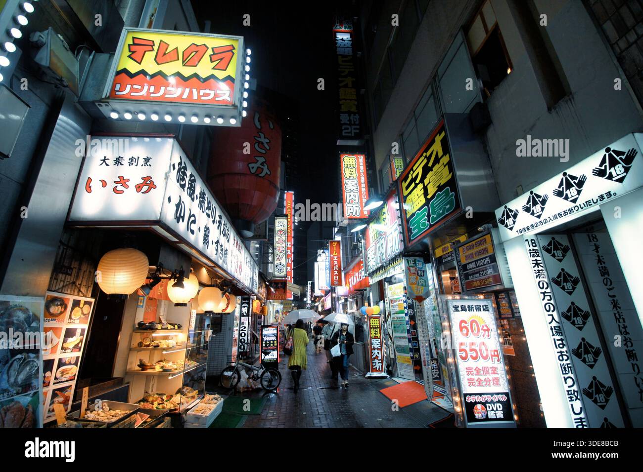 A vibrant street scene in Shinjuku at night, featuring dense neon signs ...