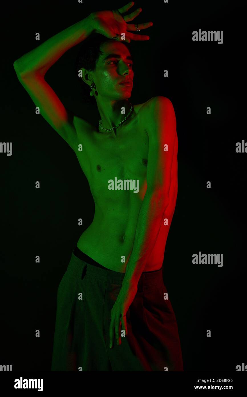 A stylish man confidently poses in vibrant green and red lights ...