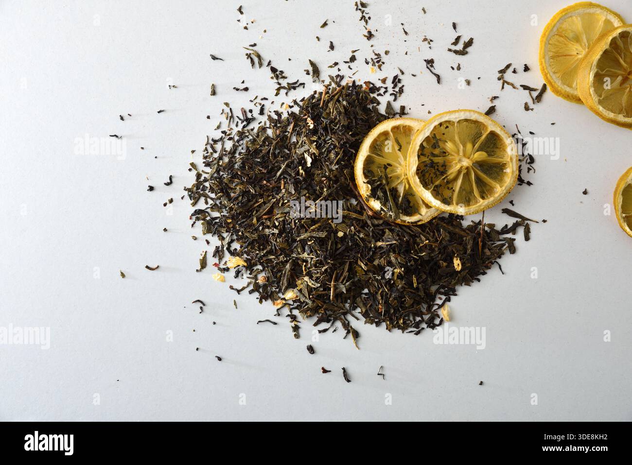 Detail of a pile of dried tea leaves isolated on a white table with lemon slices. Top view. Stock Photo