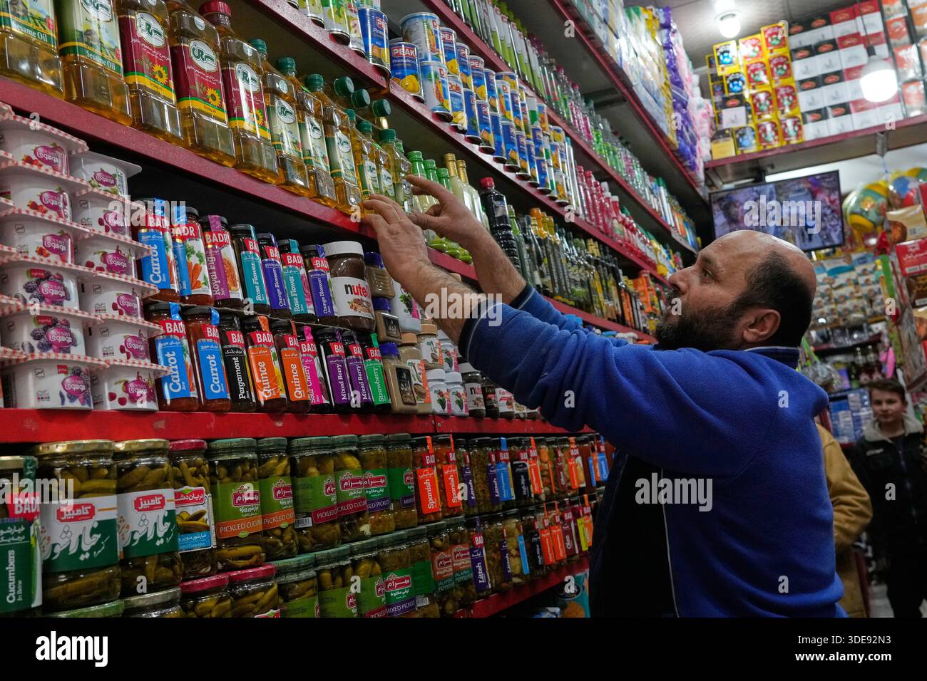 A shopkeeper arranges food oil bottles at his grocery store in northern ...