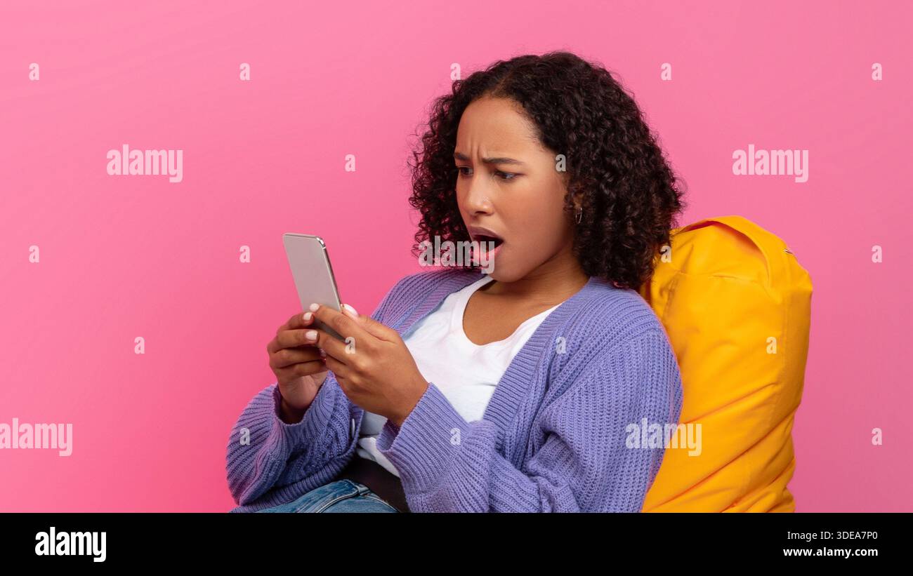Young Woman Shows Surprise While Using Smartphone in Bright Setting Stock Photo