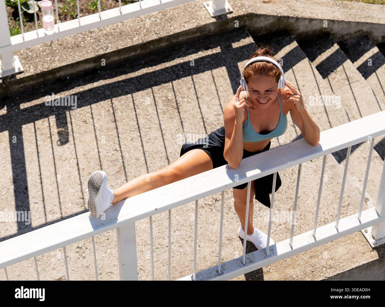 High angle view of female athlete doing stretching exercise outdoors in city. Stock Photo
