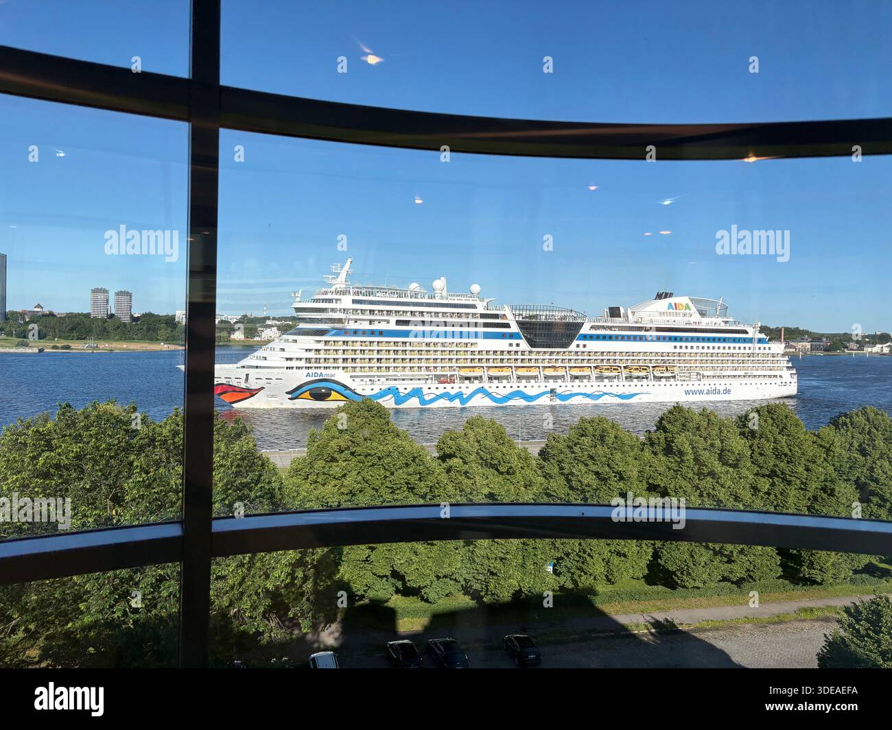 Cruise ship with colorful hull design seen through window bars, sailing under clear blue sky - Smartphone Captured Stock Image