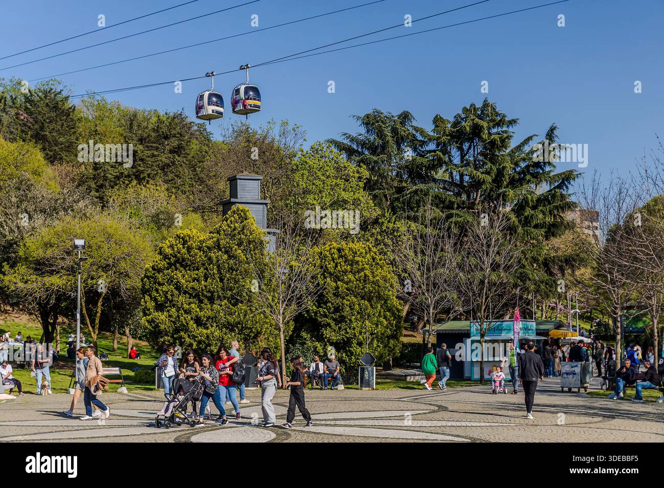 Istanbul, Turkey,  5 May 2025, People walking in Macka Democracy Park with gondola cable cars of the TF1 Macka-Taskisla Aerial Cable Car Line above th Stock Photo