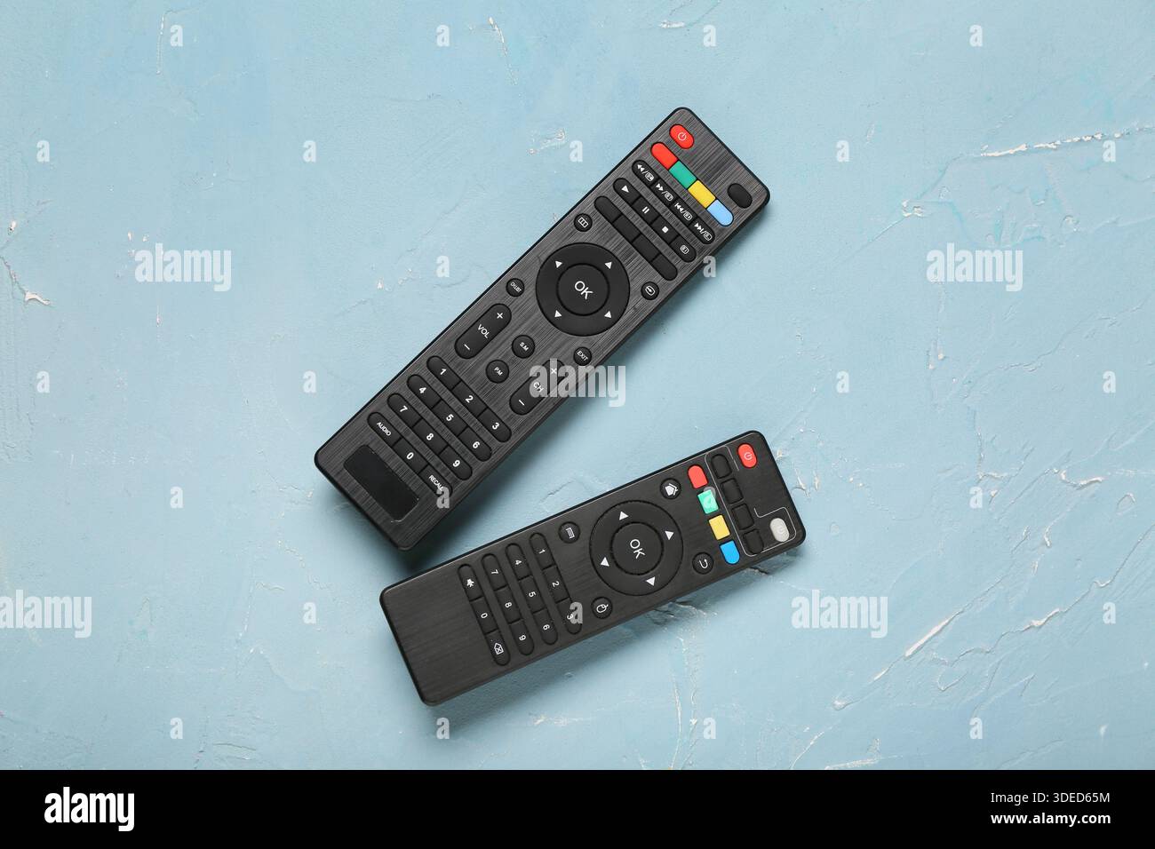 Different modern TV remote controls on blue grunge background Stock Photo