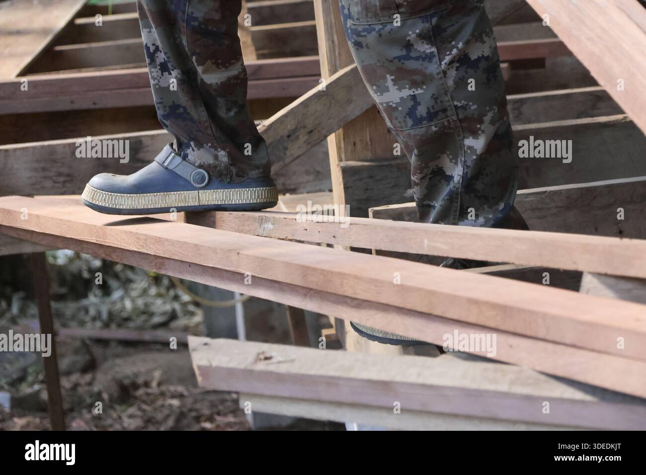 Construction worker standing carefully on wooden roof beam structure ...