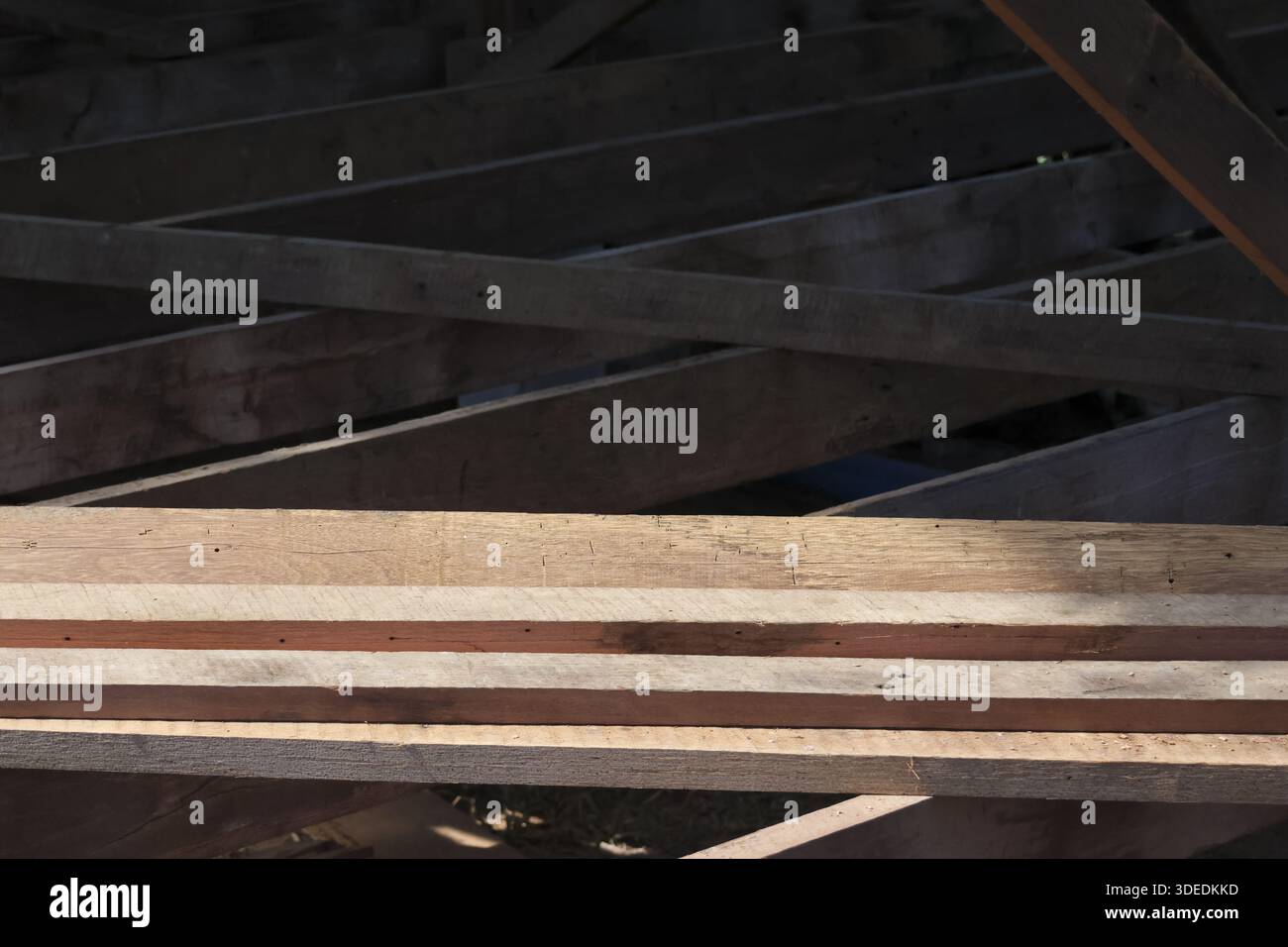 Unfinished wooden plank structure under dark roof showing construction ...