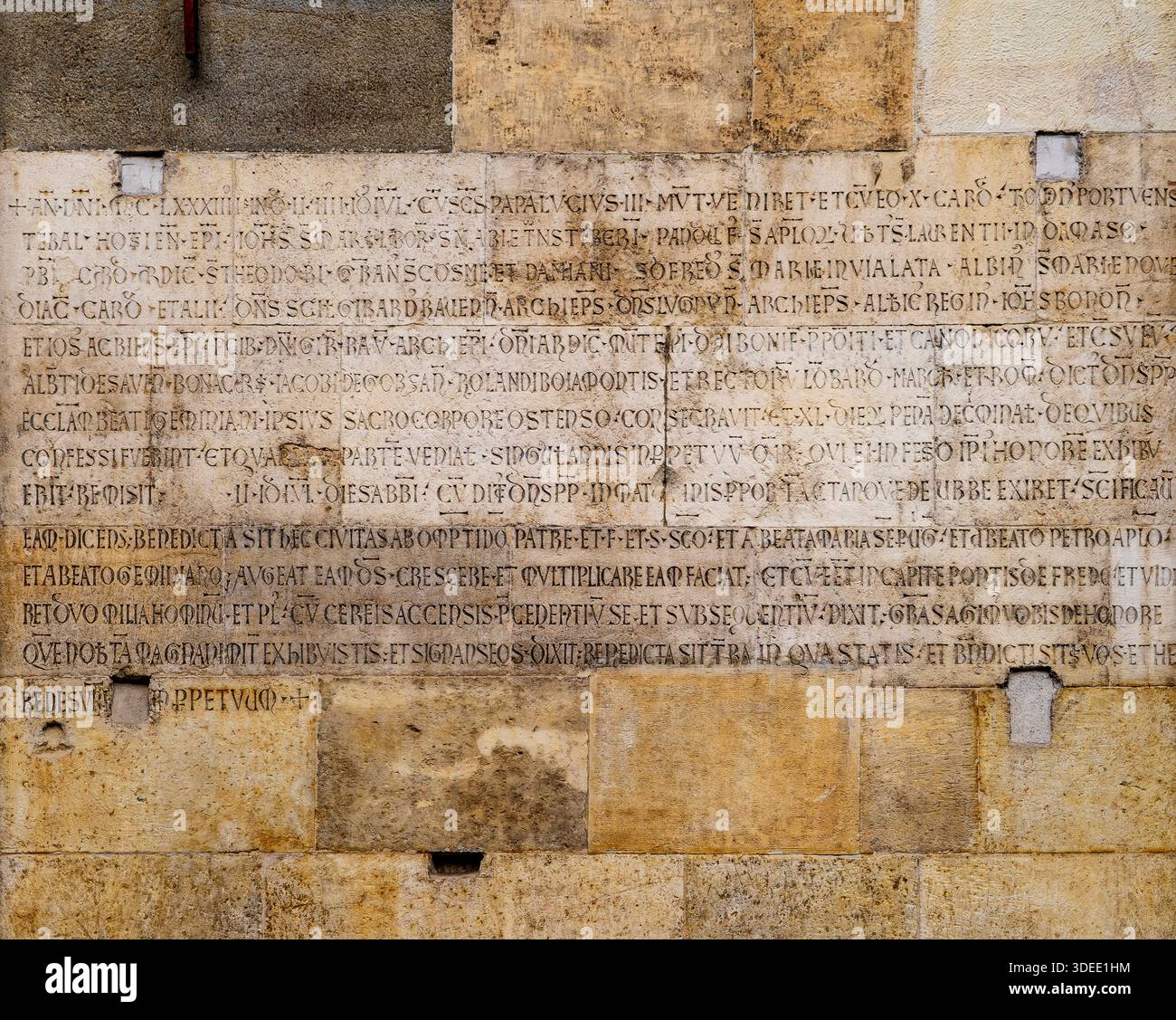 Ancient stone wall with Latin inscriptions, weathered surface. Stock Photo