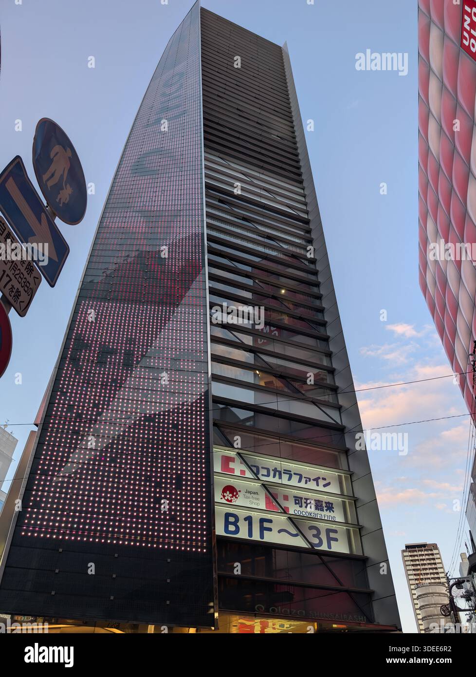 Osaka, Japan - February 2024: Modern skyscraper building featuring a large Uniqlo logo and LED display facade in the Shinsaibashi shopping district. - Smartphone Captured Stock Image