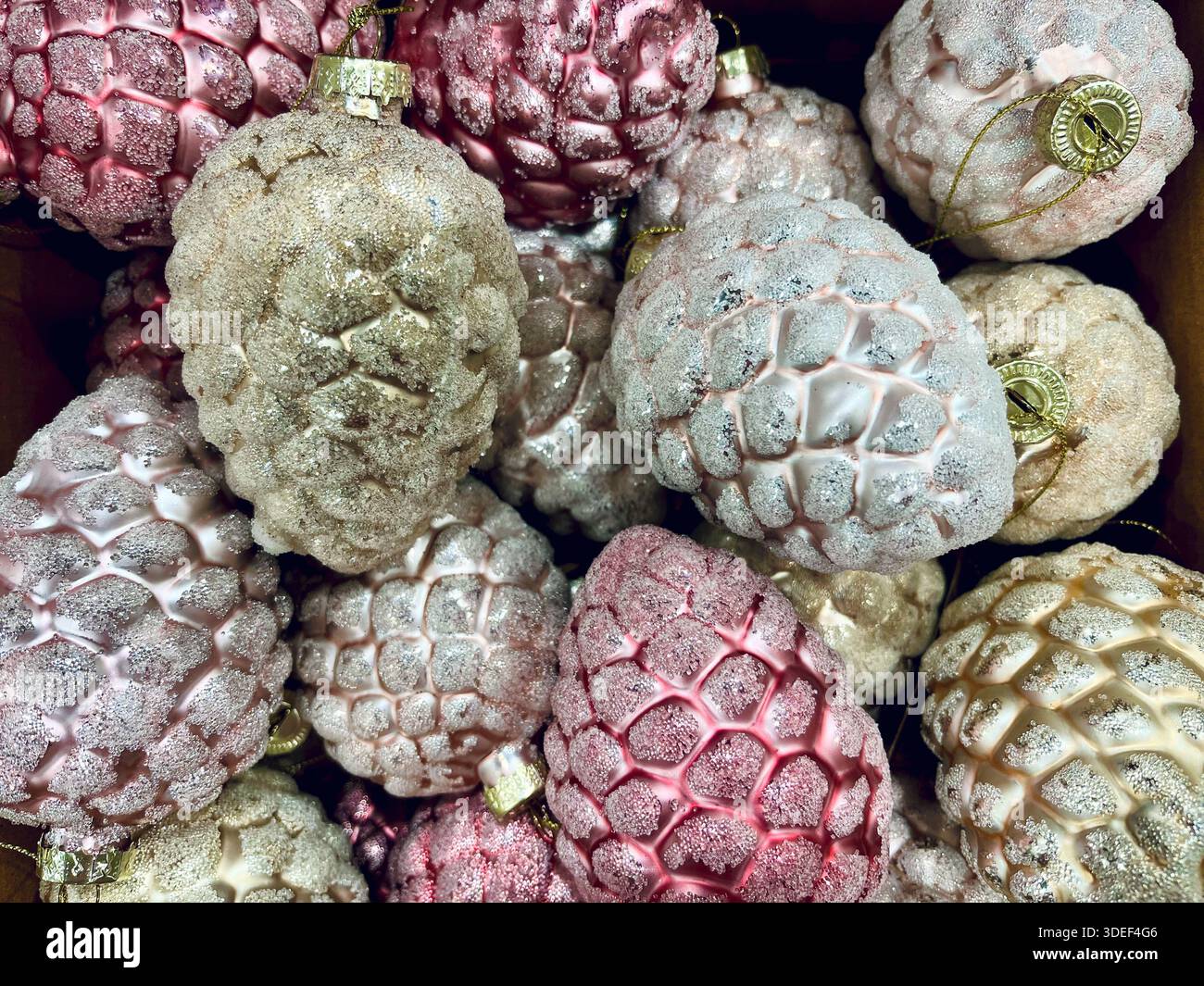 Full frame close-up of a stack of pastel coloured glitter frosted glass pinecone ornaments Stock Photo