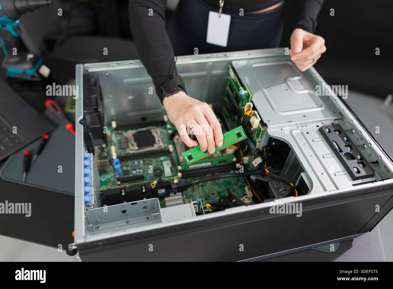 Tech worker in a server chassis upgrading RAM and components inside a desktop tower Stock Photo