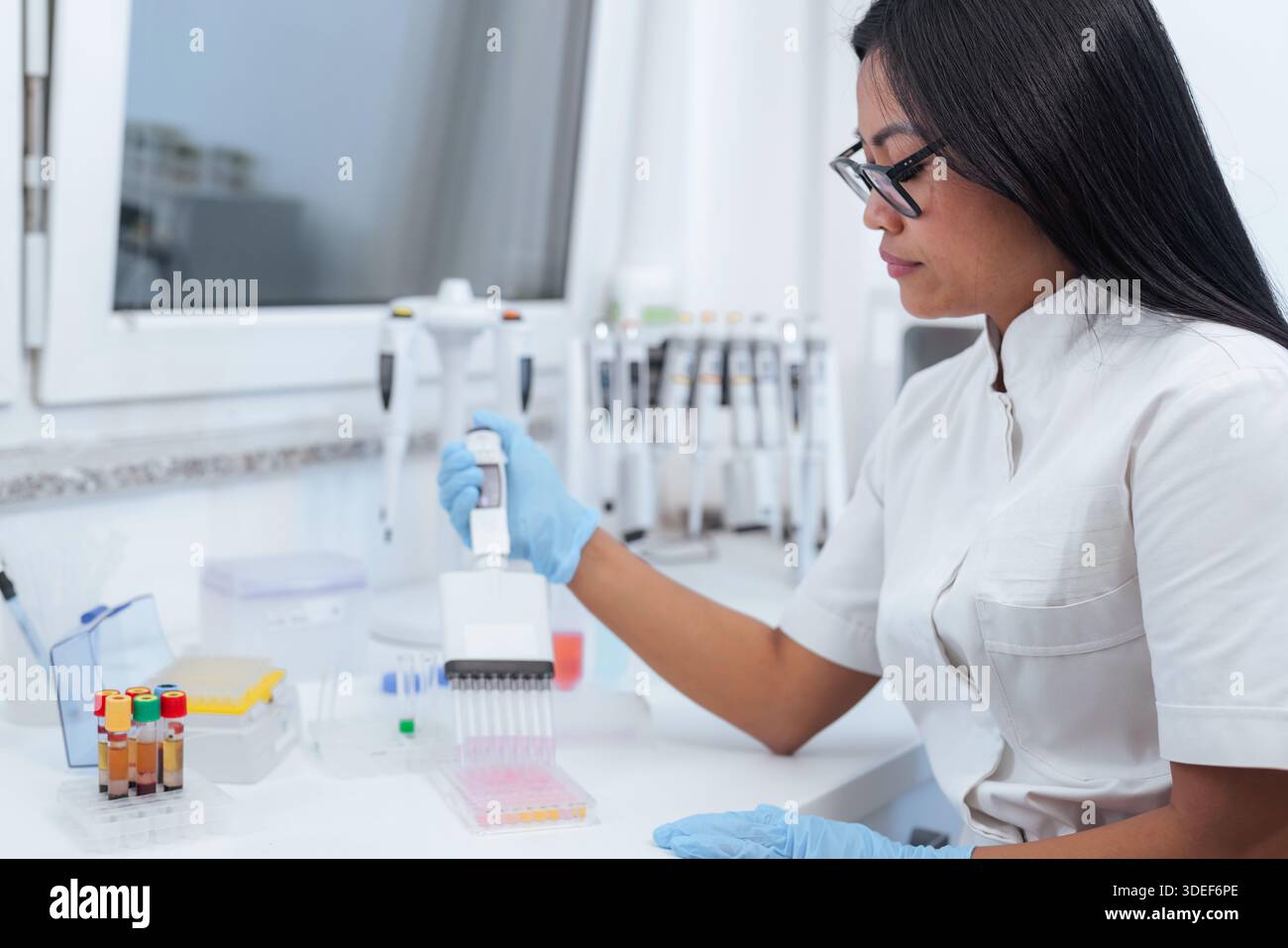 A scientist performs precise lab work while using pipettes and analyzing samples. The setting is a well-equipped pharmaceutical research laboratory. Stock Photo