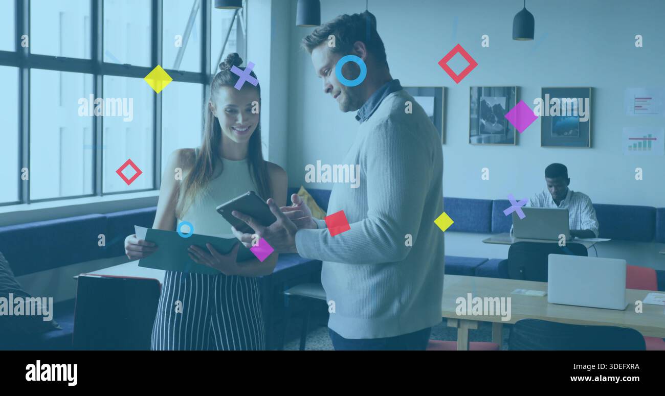 Pointing man in sweater and holding woman checking tablet and folder at coworking with graphics Stock Photo