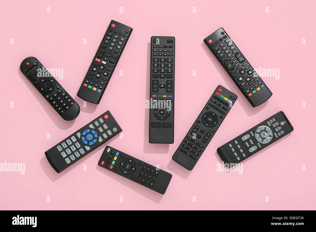 Different modern TV remote controls on pink background Stock Photo