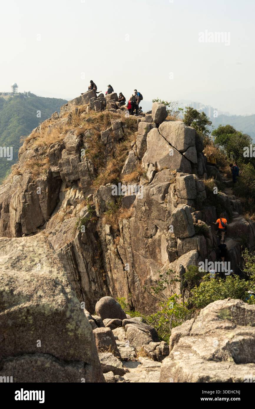 Hikers ascend Lion Rock, Hong Kong, enjoying the challenging terrain and panoramic views. Stock Photo