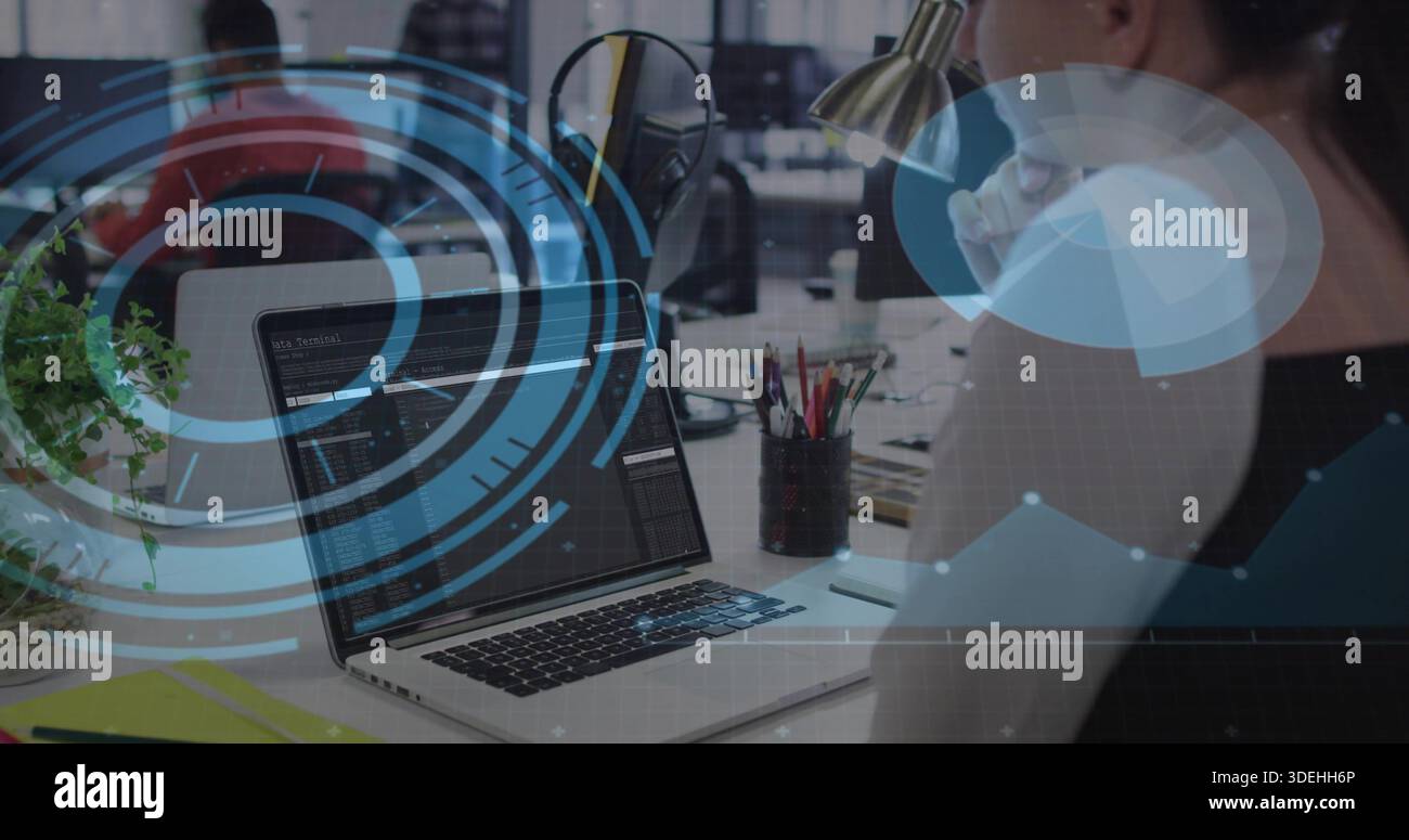 Displaying laptop screen showing code in open-plan office, developer wearing dark sleeveless top Stock Photo