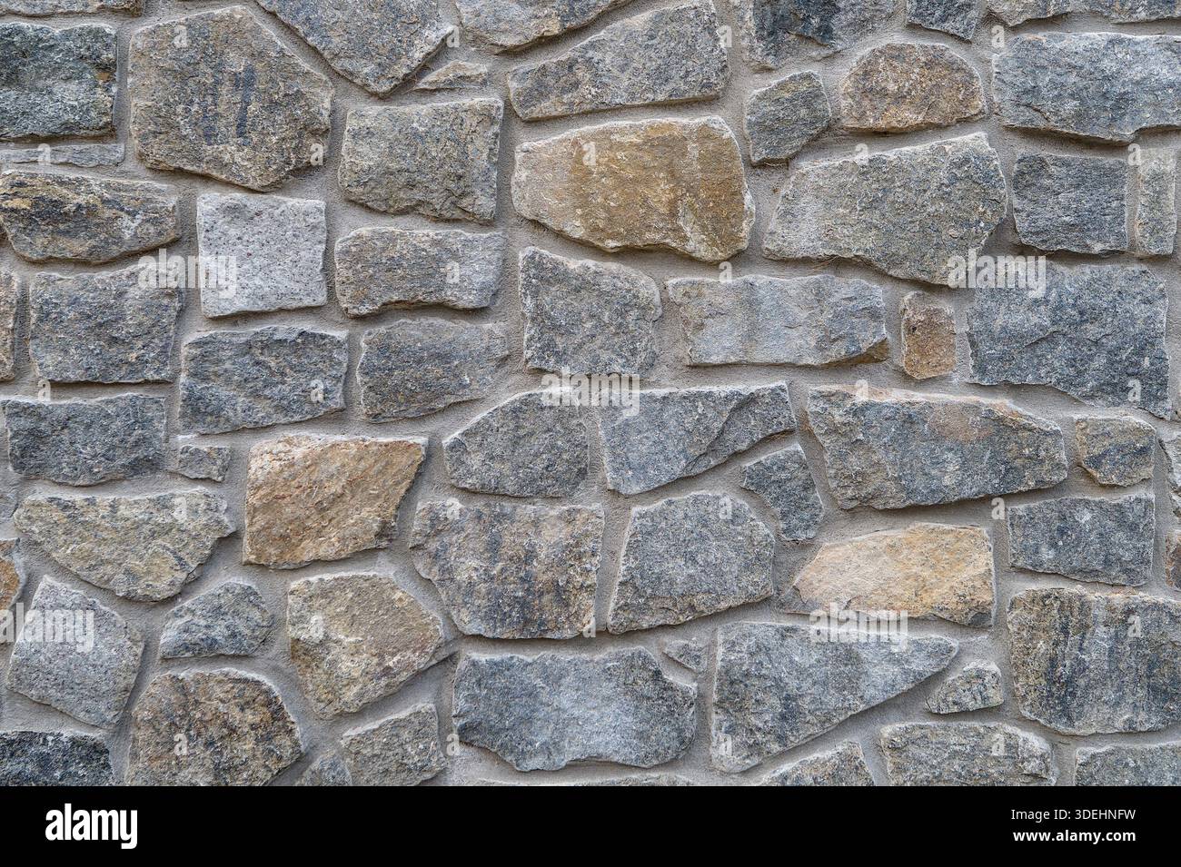 A close-up, full-frame shot of a rustic, textured natural stone wall featuring Wilmington Complex (Blue Gneiss Rocks) in Wilmington Delaware Stock Photo