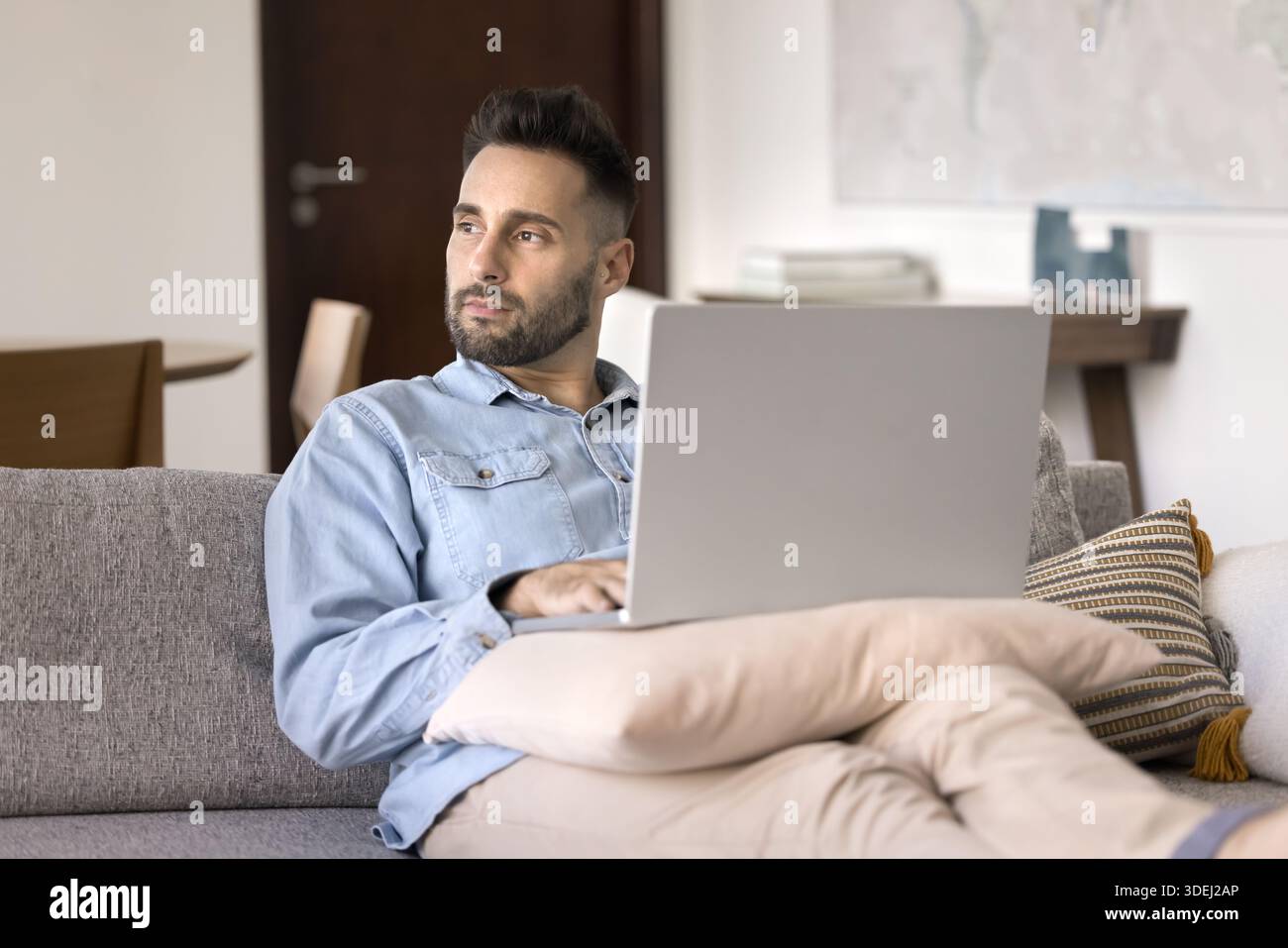 Thoughtful man working on laptop from home Stock Photo