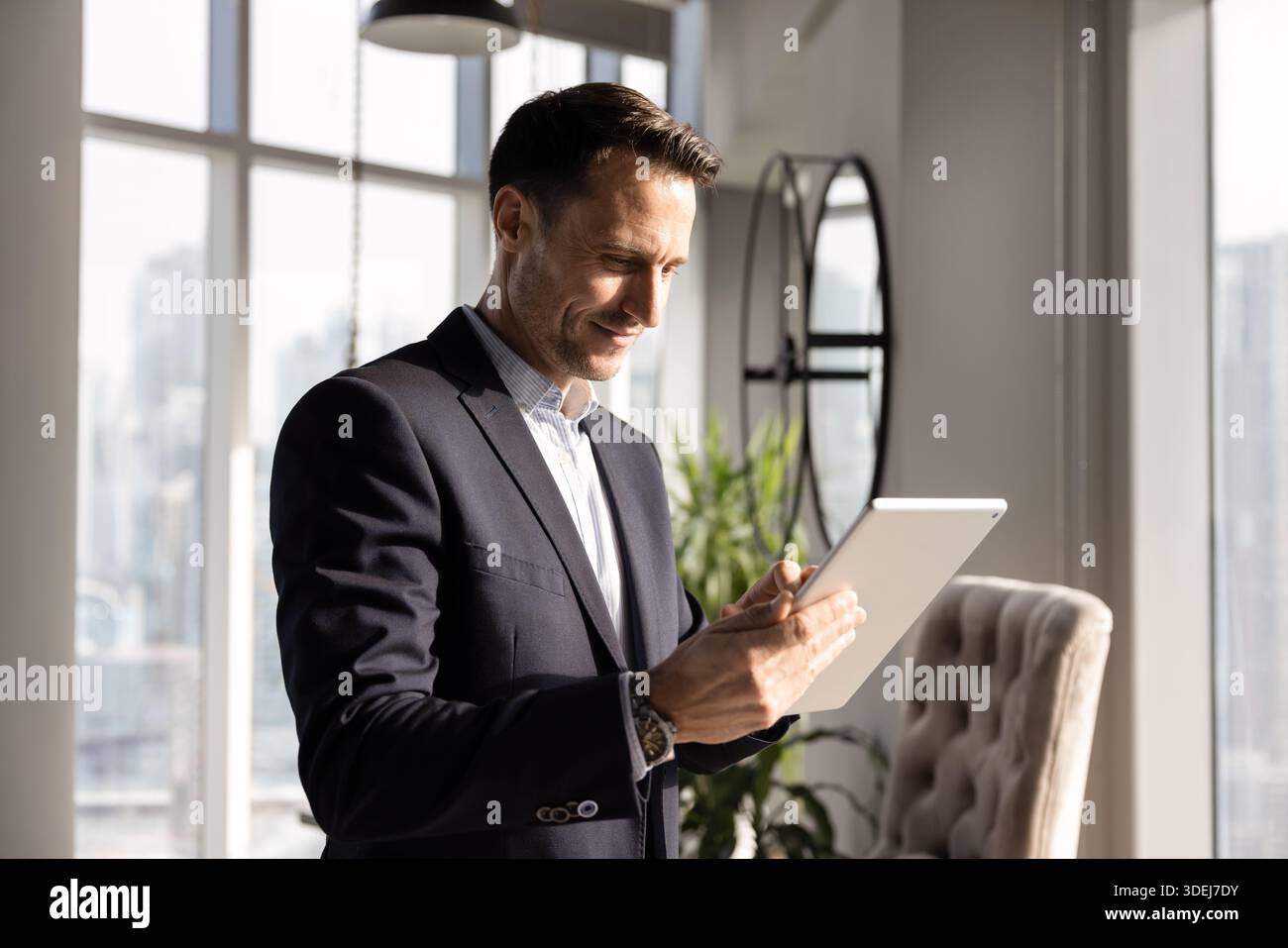 Positive young Hispanic executive man typing on tablet Stock Photo
