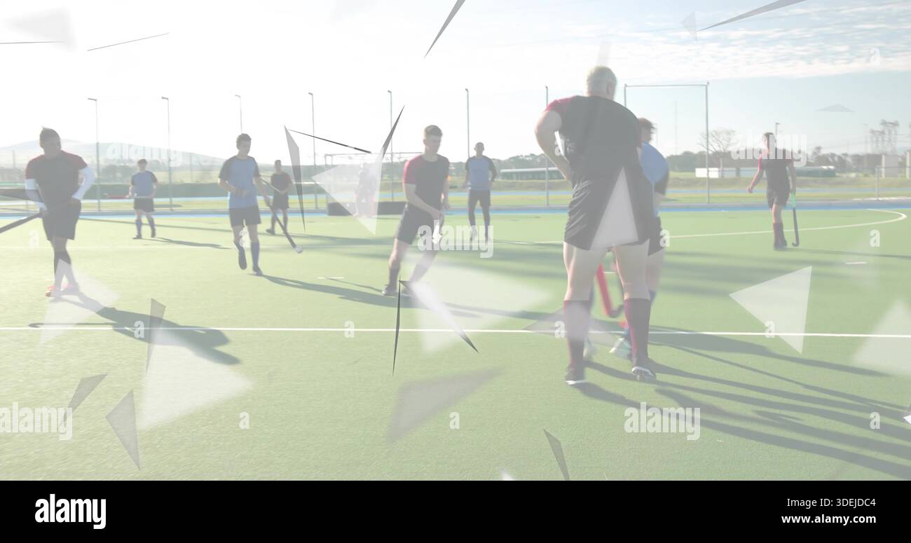 Standing hockey player in dark red kit watching play on turf, with sticks and triangular overlays Stock Photo