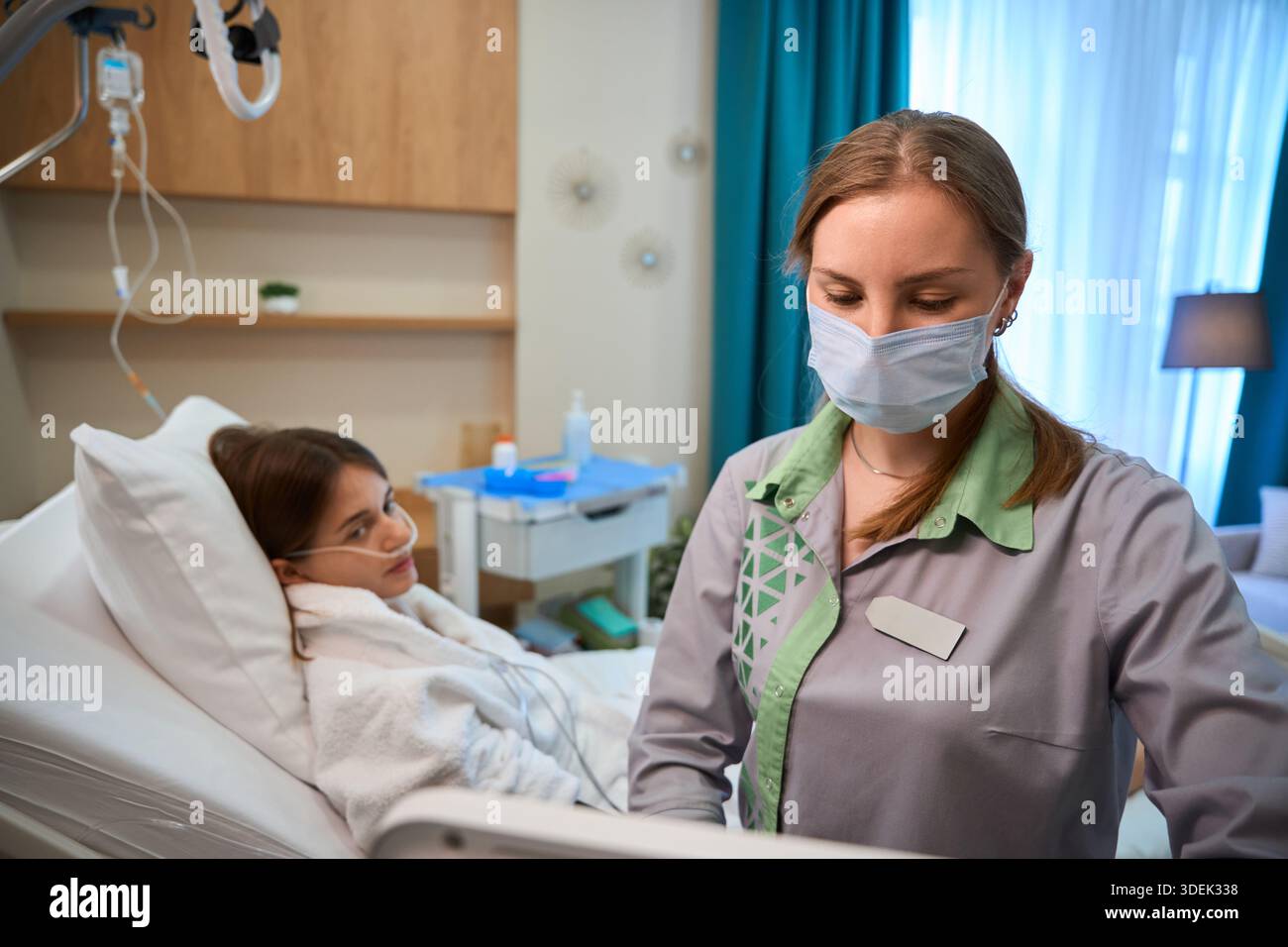 Nurse wearing mask setting up oxygen therapy for hospital patient Stock ...