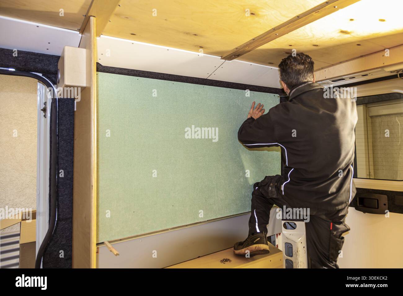 Camper van conversion. man working on fabrics wall in Transporter. Conversion DIY Jumper van Stock Photo