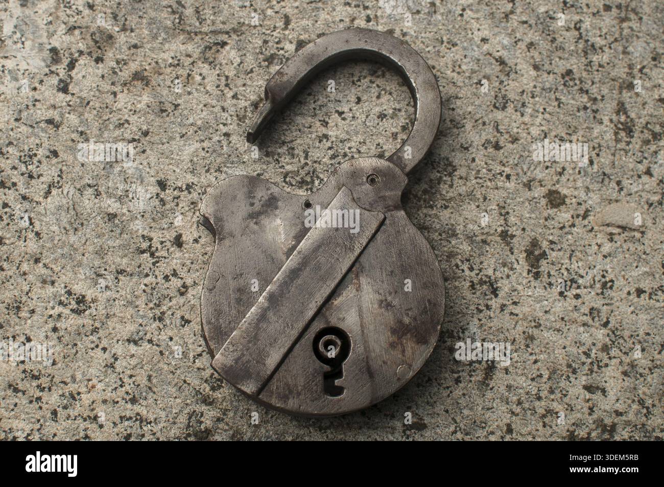 Old weathered grunge retro open padlock closeup on solid stone surface background Stock Photo
