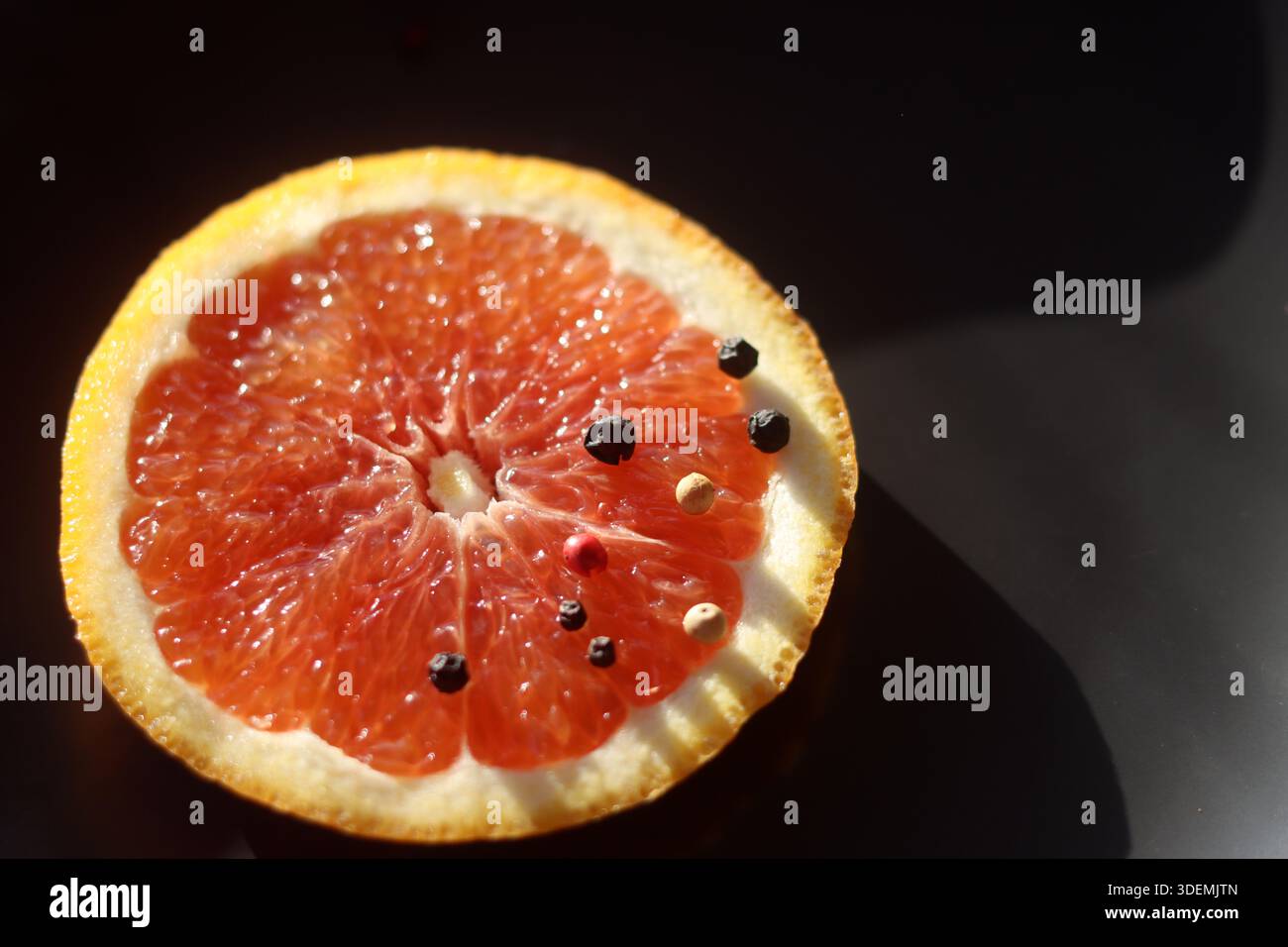 Grapefruit with black pepper on a black background Stock Photo
