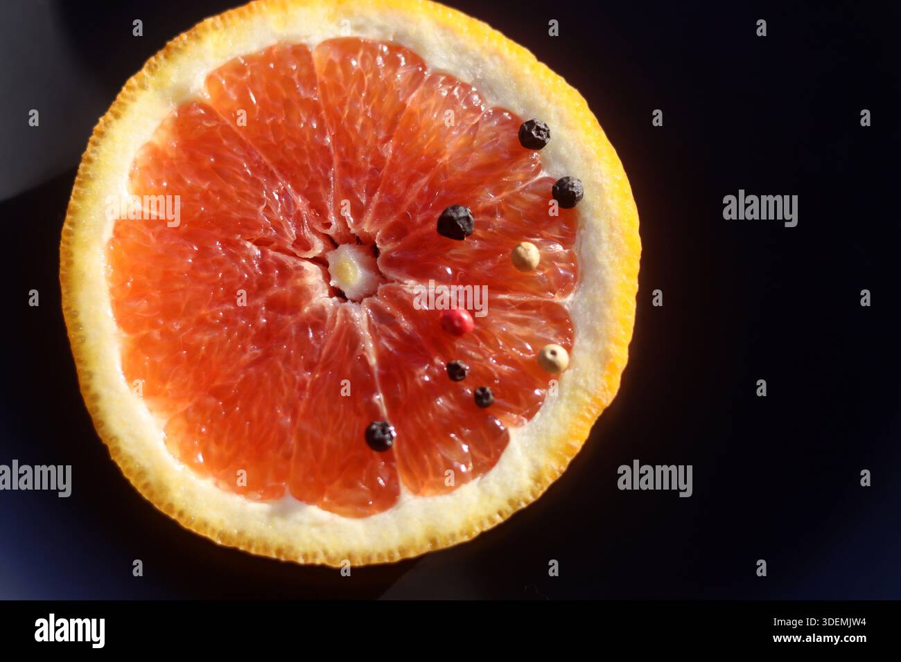 Grapefruit with black pepper on a black background Stock Photo