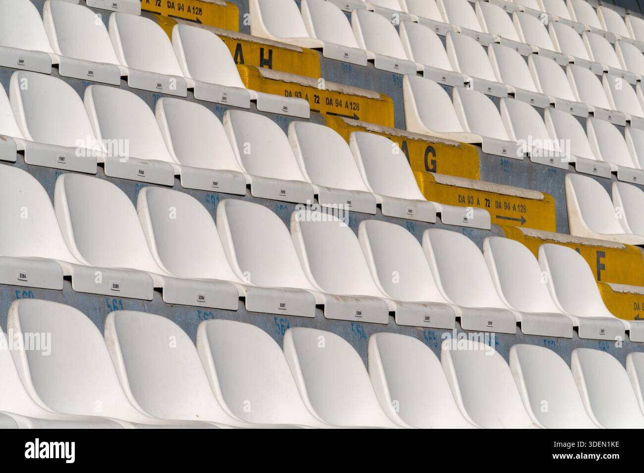 Rows of white and yellow stadium seats arranged in a repeating pattern Stock Photo